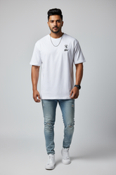 Man wearing a white t-shirt with a logo and light blue jeans on a gray background