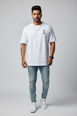 Man wearing a white t-shirt with a logo and light blue jeans on a gray background